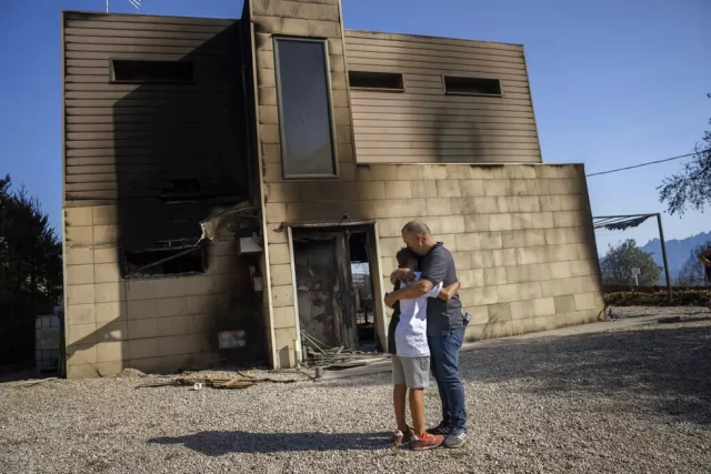 Homem abraça filho diante da casa da família, no nordeste da Espanha, queimada por um dos centenas de focos de incêndios ativos na Espanha, em 19 de julho de 2022. — Foto: AP